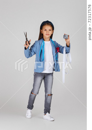adorable little girl holding tape measure and spool of thread 72317576