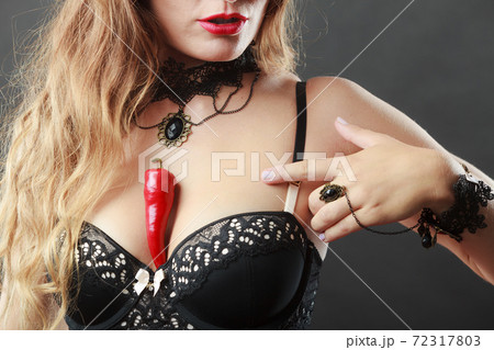 Woman wearing sexy lingerie holding chilli on chest 72317803