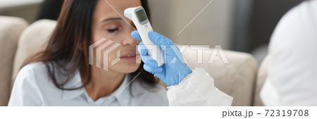 Doctor in protective suit measures temperature with noncontact infrared thermometer 72319708