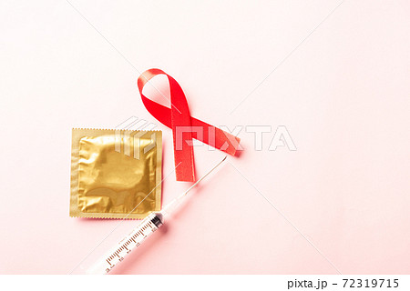 Red bow ribbon symbol HIV, AIDS cancer awareness, condom and syringe Red bow ribbon symbol HIV, AIDS cancer awareness, condom and syringe 72319715