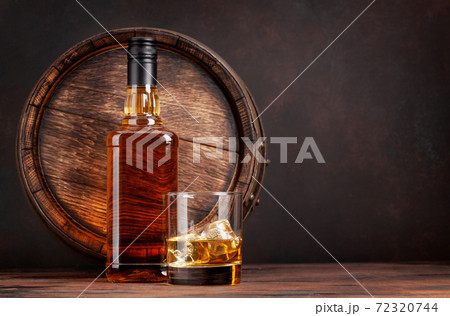 Scotch whiskey bottle, glass and old barrel 72320744