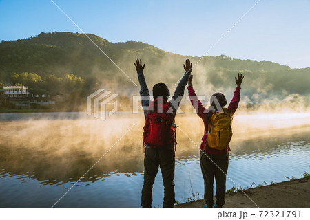 Asian woman and Asian man which backpacking standing near the lake, she was smiling, happy and enjoying the natural beauty of the mist. 72321791
