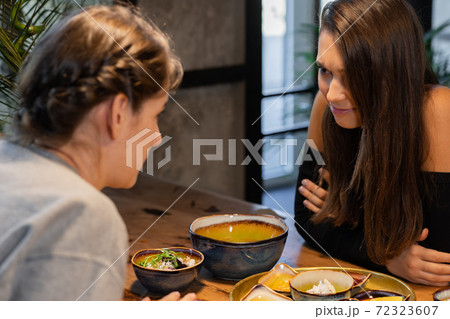 Two highschool girls gossiping in an asian cafe 72323607