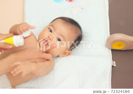 お風呂上りの赤ちゃんに保湿クリームを塗るの写真素材