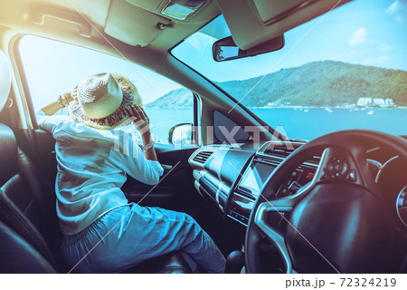 Woman drive a car travel relax to the beach in the summer holiday. Looking out of the car window to see the beautiful mountains and sea landscape. Promthep Cape, Phuket Thailand. Woman drive a car travel relax to the beach in the summer holiday. Looking out of the car window to see the beautiful mountains and sea landscape. Promthep Cape, Phuket Thailand. 72324219