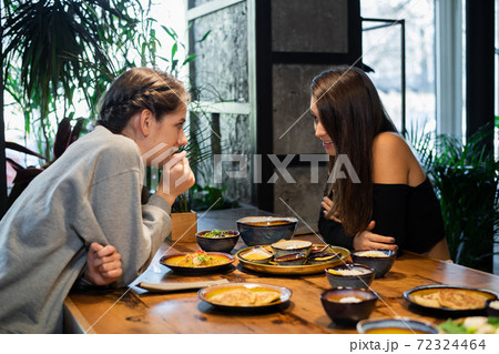 Two highschool girls gossiping in an asian cafe Two highschool girls gossiping in an asian cafe 72324464