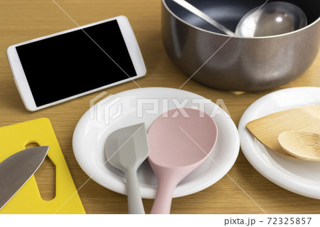 スマートフォンを見ながら料理をするイメージ 72325857