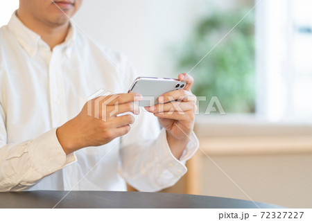 リビングでスマホをみる若い男性の手元 リビングでスマホをみる若い男性の手元 72327227