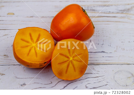 Tasty ripe persimmon fruits on a white wooden table Tasty ripe persimmon fruits on a white wooden table 72328002