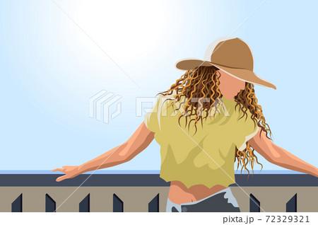 Woman in sun hat , yellow cropped t-shirt and jeans posing on the balcony 72329321