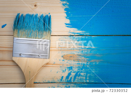 Painting works background with paintbrush in blue paint on the wooden not completely painted boards 72330352