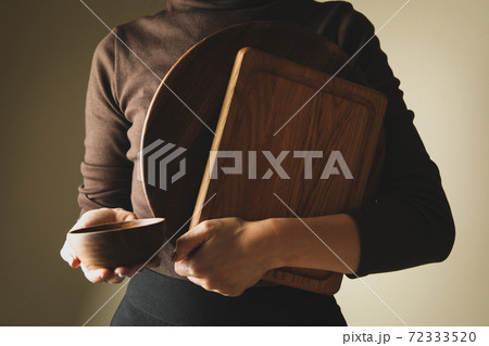 Young woman in sweater holding wooden kitchenware 72333520