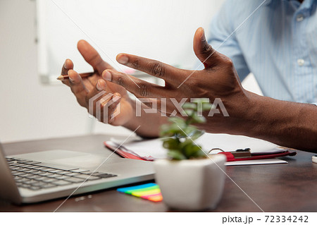 Online english courses at home. Close up hands of man during teaching students remotely in interior of living room Online english courses at home. Close up hands of man during teaching students remotely in interior of living room 72334242