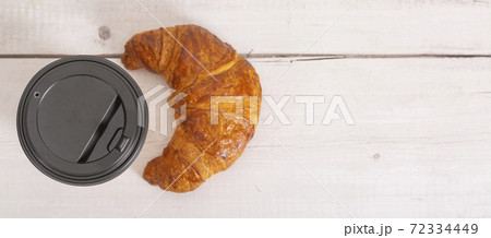 Paper cup of coffee and croissant on a light wooden background. Close-up. copy space. Free space for text. top view. Soft focus Paper cup of coffee and croissant on a light wooden background. Close-up. copy space. Free space for text. top view. Soft focus 72334449