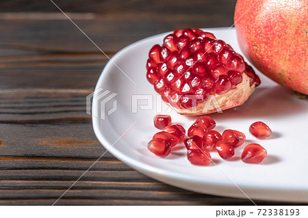 Craked ripe pomegranate on dark wooden background Craked ripe pomegranate on dark wooden background 72338193