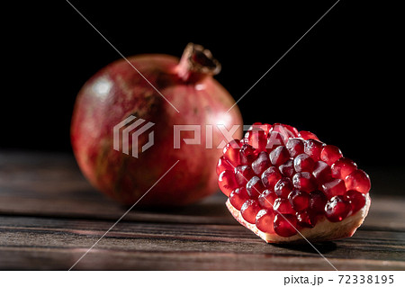 Craked ripe pomegranate on dark wooden background 72338195