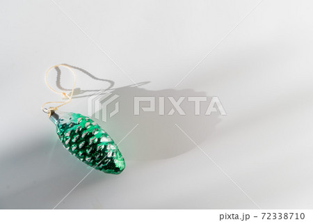 Green pine cone glass vintage christmas bauble on white background with sunlight and shadow 72338710