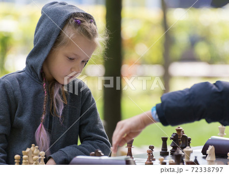 Smart Girl, seven years old is taking part a kids chess tournament outdoor in the park. Smart Girl, seven years old is taking part a kids chess tournament outdoor in the park. 72338797