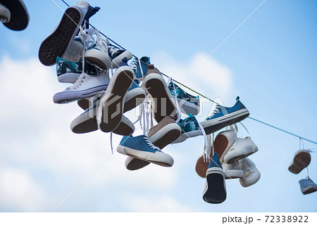 Pairs of sneakers hanging on cable 72338922