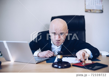 Angry notary, lawyer, attorney with a gavel in his hand in his notary office. Angry notary, lawyer, attorney with a gavel in his hand in his notary office. 72339722