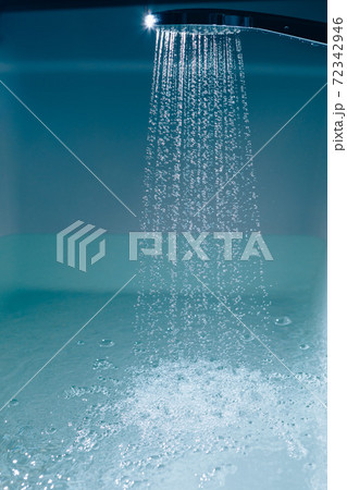 shower filling a bathtub with water stream 72342946