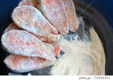 Cooking fish dishes. Raw pieces of pink salmon or chum salmon in breadcrumbs are on the plate.  72343341
