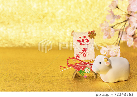 金紙と桜を背景に迎春と寿が書いてある飾りと丑年のフィギュアのグリーティングカード。 金紙と桜を背景に迎春と寿が書いてある飾りと丑年のフィギュアのグリーティングカード。 72343563