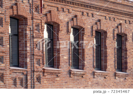 Brick wall of an old 19th century building with large windows. Wall of an old red brick building with five windows 72345467
