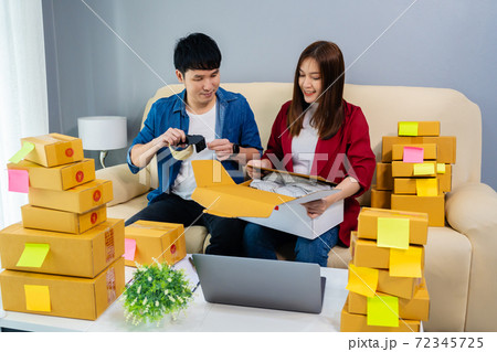 couple online entrepreneur using tape to packing parcel box at home office, prepare product for deliver to customer, (SME business) 72345725
