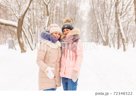 Two girls are walking in a winter park in the snow. 72346522