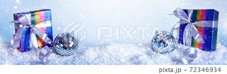 Blue Christmas banner with rainbow colors gift box and disco ball in snowdrift, copy space Blue Christmas banner with rainbow colors gift box and disco ball in snowdrift, copy space 72346934