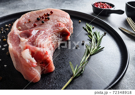 Raw Pork Loin chops in a black round plate on a 72348918