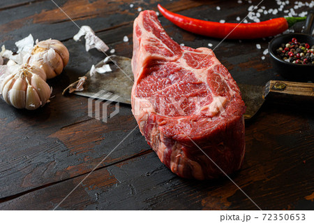 Raw dry Cowboy steak on dark wooden vintage table Raw dry Cowboy steak on dark wooden vintage table 72350653