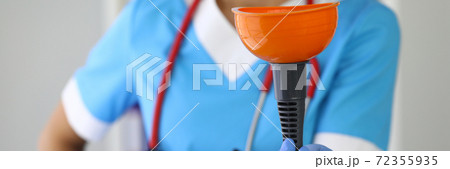 Nurse with stethoscope around neck in rubber gloves holds plunger closeup 72355935