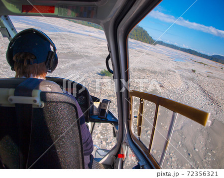 Helicopter cockpit view over broad river bed Helicopter cockpit view over broad river bed 72356321