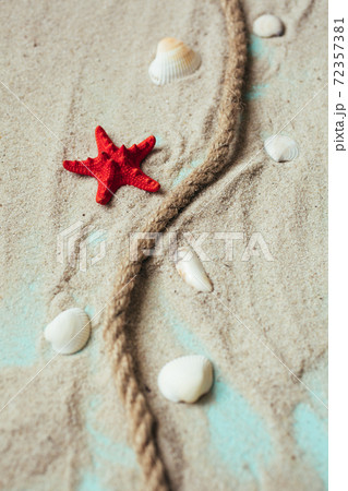 Mooring rope, seashells and red starfish on sand on blue wooden table background. Mooring rope, seashells and red starfish on sand on blue wooden table background. 72357381