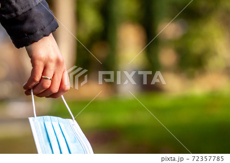 Woman, standing at the grave of family members with a facemask during the pandemic 72357785