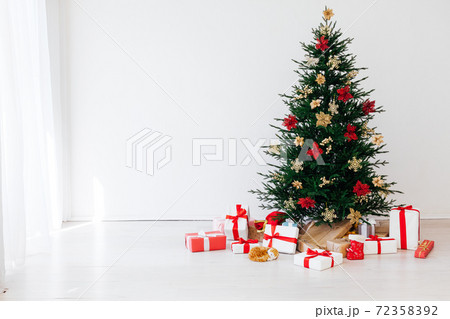 decorated Christmas tree with New Year's gifts in a room with a window decorated Christmas tree with New Year's gifts in a room with a window 72358392