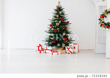 decorated Christmas tree with New Year's gifts in a room with a window decorated Christmas tree with New Year's gifts in a room with a window 72358393