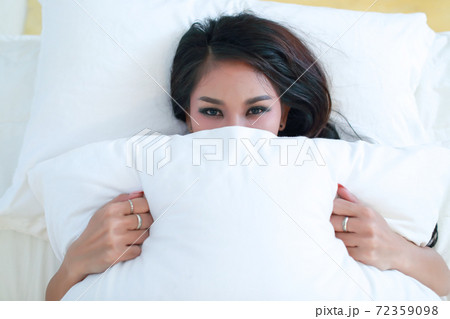 portrait of beautyful model with black see through dress closing her mouth with pillows 72359098