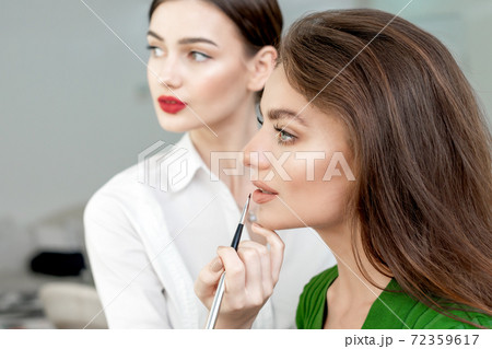 Makeup artist applies lipstick. 72359617
