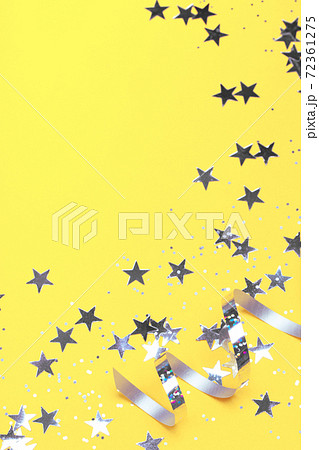 Shiny party streamers and stars on the trendy yellow background Shiny party streamers and stars on the trendy yellow background 72361275