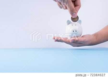 Hand putting money coin into piggy bank isolated grey background. Property investment and house mortgage financial concept. 72364027