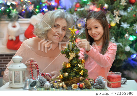 Smiling little girl with grandmother preparing for Christmas 72365990