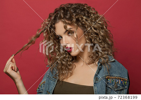Nice woman with curly hair posing on red background 72368199