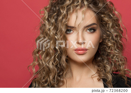 Beautiful woman face. Perfect female model with curly hair on red background 72368200