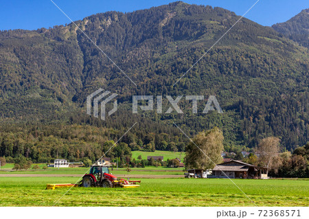 tractor in a field on a farm cutting grass for cattle feeding tractor in a field on a farm cutting grass for cattle feeding 72368571