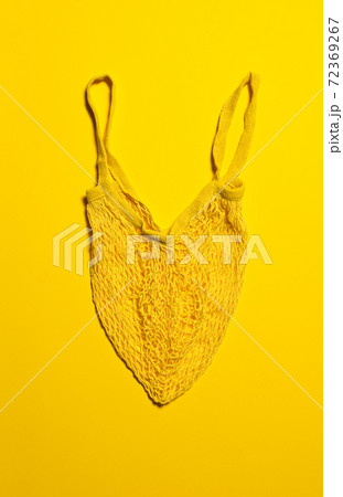 Bright yellow mesh bag on yellow paper Bright yellow mesh bag on yellow paper 72369267
