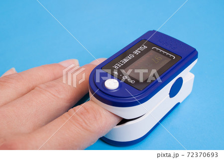 One pulse oximeter on finger on blue backgroundの写真素材 [72370693] - PIXTA