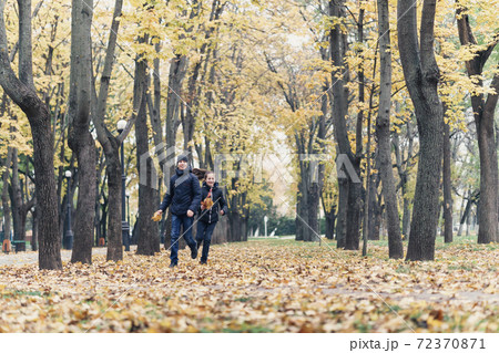 teen girl and boy running through the park and enjoys autumn, beautiful nature with yellow leaves 72370871
